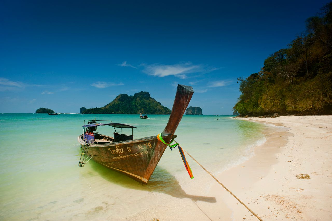 menu-01 Scenic view of a traditional longtail boat on Ao Nang's turquoise beach in Krabi, Thailand.