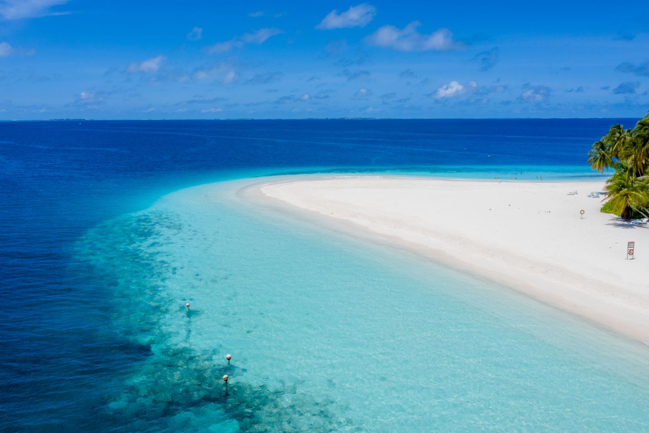 Aerial view of a serene tropical beach with turquoise waters in Guraidhoo, Maldives.