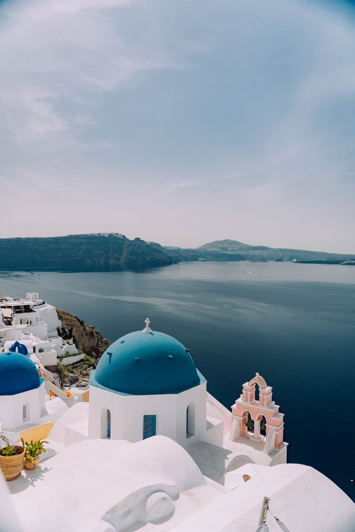 Menu Greece's Santorini with blue domes and sea, perfect summer getaway.
