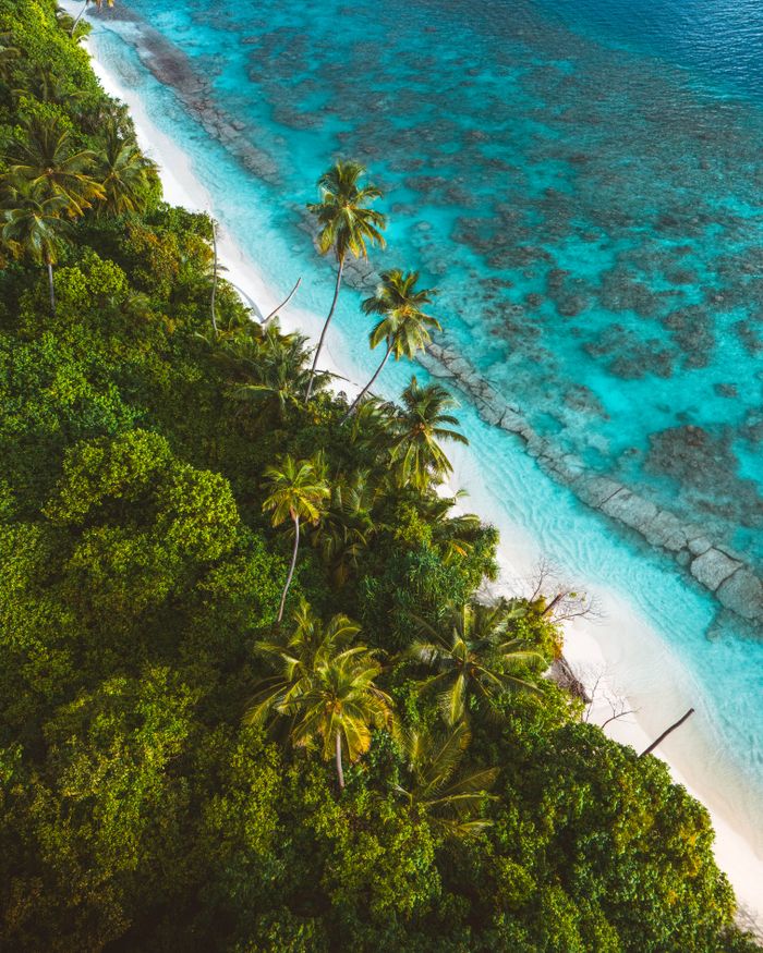 Menu A stunning aerial view of a tropical island with lush greenery and turquoise waters.