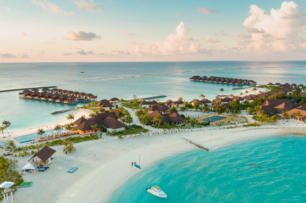 Menu Stunning aerial view of a luxurious tropical resort in the Maldives, showcasing overwater bungalows and turquoise waters.